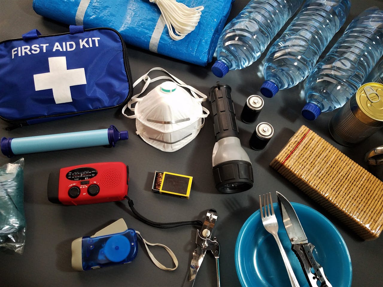Offerings Flat lay of essential emergency survival kit items including first aid and water bottles.